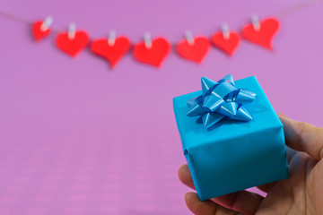 Red love hearts and female hand with small gifts on pink background.