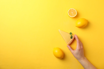 Person hold slice of lemon tart on yellow background, top view