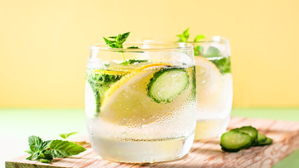 Healthy refreshing summer cocktail or mocktail without alcohol with lemon and cucumber. Summer detox drink on fresh green background, healthy living, top view