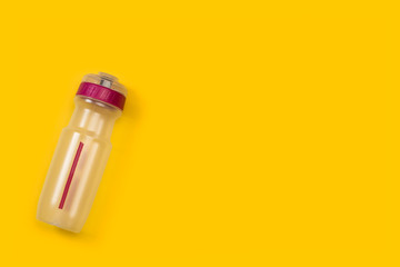 Botella para deporte de plástico sobre fondo liso amarillo brillante. Vista Superior. Copy space. Concepto: Fitness
