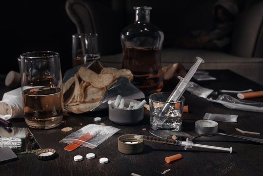 Various drugs, alcohol and cigarettes are on the wooden table. Substances that cause drug and alcohol dependence. Low key.