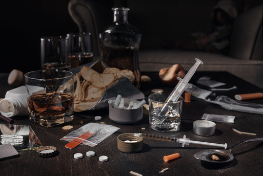 Various drugs, alcohol and cigarettes are on the wooden table. Substances that cause drug and alcohol dependence. Low key.