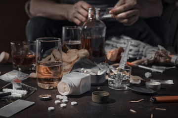 Various drugs, alcohol and cigarettes are on the wooden table. Substances that cause drug and alcohol dependence. Low key.
