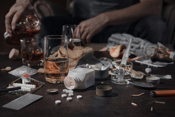Various drugs, alcohol and cigarettes are on the wooden table. Substances that cause drug and alcohol dependence. Low key.