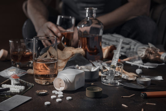 Various drugs, alcohol and cigarettes are on the wooden table. Substances that cause drug and alcohol dependence. Low key.