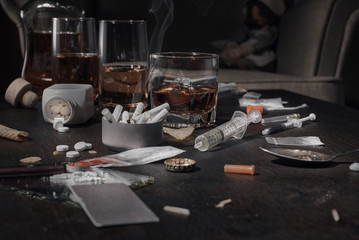 Naklejka na ściany i meble Various drugs, alcohol and cigarettes are on the wooden table. Substances that cause drug and alcohol dependence. Low key.