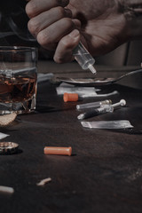Various drugs, alcohol and cigarettes are on the wooden table. Substances that cause drug and alcohol dependence. Low key.