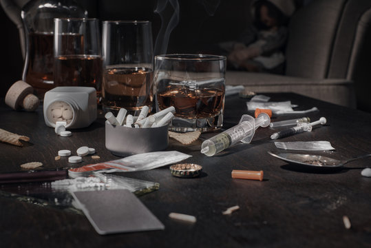 Various drugs, alcohol and cigarettes are on the wooden table. Substances that cause drug and alcohol dependence. Low key.