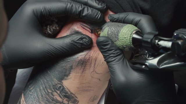 Shooting of man tattooist getting tattoo of snake, closeup