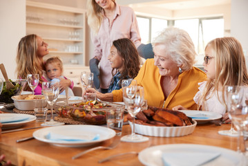 Mother Serving Food As Multi-Generation Family Meet For Meal At Home