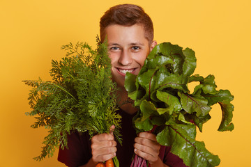 Close up portrait of young active cheerful handsome young man covering his face with green, smiling sincerely, being in for healthy food, sticking to healthy diet, being vegeterian. Vegan concept.