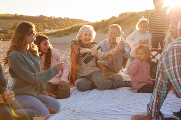 Multi-Generation Family Opening And Pouring Champagne To Celebrate At Winter Beach Vacation