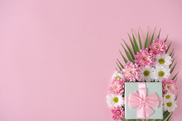Creative layout made with palm leaf, pink and white flowers on pastel pink background. Flat lay. Spring minimal concept.