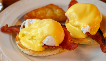Weekend brunch in Scotland with two eggs benedict on homemade muffuns with roasted bacon and yellow hollandaise sauce.