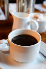 White cup with black coffee and  hot milk jug