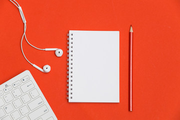 Creative flat lay photo of workspace desk with copy space. Top view office desk with notepad, red background