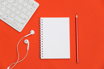 Notebook, keyboard with mouse, headphones and pencil on red background. Top view. Flat lay
