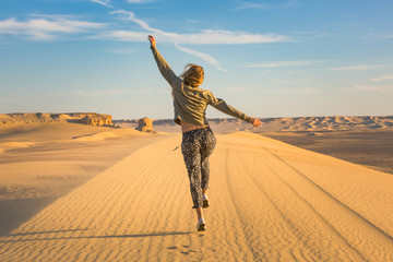 Happy girl jumping in the desert celebrating her freedome