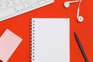 Minimal workplace with blank notepad, keyboard and supplies on colored background. Top view. Flat lay