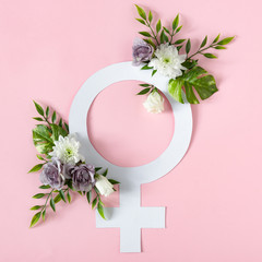Gender symbol with flowers and leaves on pink background. Venus or female sign minimal concept....