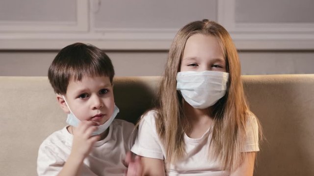 Sad funny children, a boy and a girl put respiratory masks on their mouths and noses. The concept of protection from SARS. Isolation of infected people