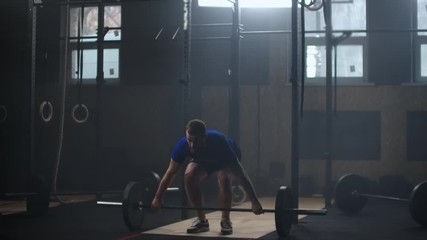 Strong man doing barbell snatch exercise at the gym in slow motion
