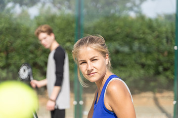 Naklejka premium Girl with a paddle racket in front of a young boy on a paddle court