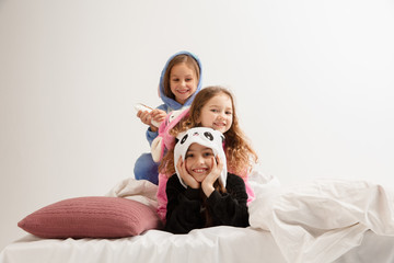 Children in soft warm pajamas colored bright playing at home. Little girls having fun, party, laughting, playing together, look stylish and happy. Concept of childhood, leisure activity, happiness.