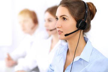 Call center. Focus on beautiful business woman using headset in sunny office