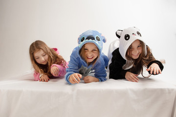 Children in soft warm pajamas colored bright playing at home. Little girls having fun, party,...