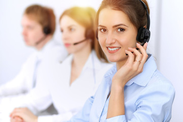 Call center. Focus on beautiful business woman using headset in sunny office