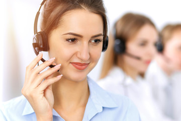 Call center. Focus on beautiful business woman using headset in sunny office