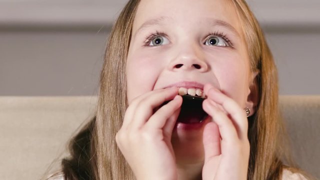 Pretty, kind girl inserts a stylish single-jawed orthodontic correction plate into her mouth. Alignment of teeth from a young age