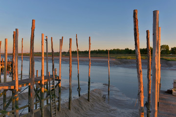 wooden poles lighting by sun at sunset in front of the sea