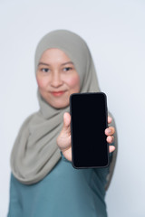 Beautiful muslim woman holding her mobile phone with phone in focus