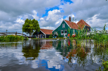 Fototapeta premium Zaanse Schans, Holland, August 2019. Northeast Amsterdam is a small community located on the Zaan River. View of the pretty wooden houses of the village, mainly green in color. Cloudy day.