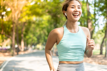 Fototapeta premium Running Asian woman. Female Runner Jogging during Outdoor Workout in a Park. Asian woman running in garden. Her morning exercise.