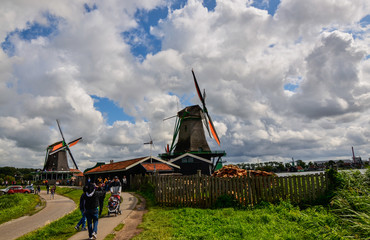 Zaanse Schans, Holland, August 2019. Northeast Amsterdam is a small community located on the Zaan River. View of the mills on the river bank, they stand out with their bright colors. Cloudy day.