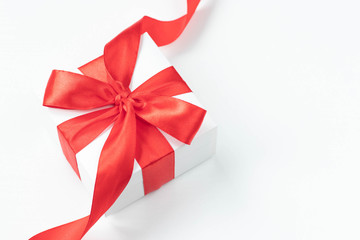 White gift box with  red ribbon on white background. Top view. Holiday time at any time of the year