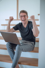 close up. happy young man with laptop sitting on steps