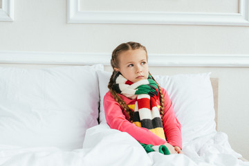 Obraz na płótnie Canvas sad diseased child in scarf sitting on bed