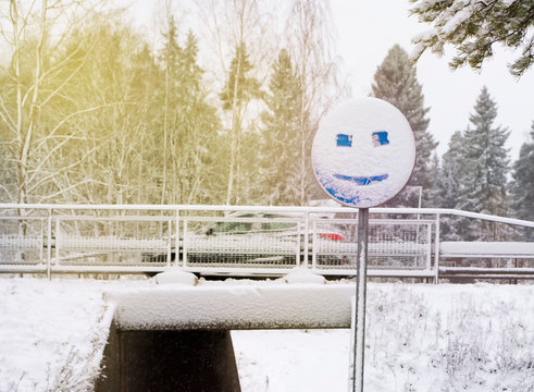 Snow covered road sign and emoticon drawn. Winter mood