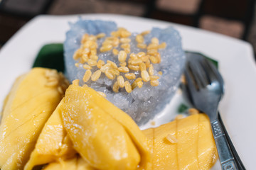 Mango Sticky Rice with a fork ans spoon on a wooden table