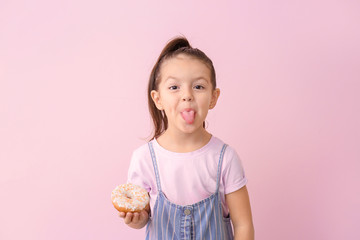 Funny little girl with donut on color background