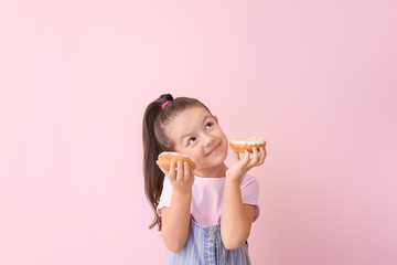 Funny little girl with donuts on color background