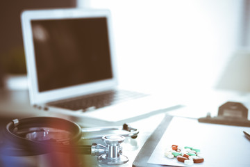 Stethoscope, prescription medical form lying on glass table with laptop computer. Medicine or pharmacy concept. Medical tools at doctor working table