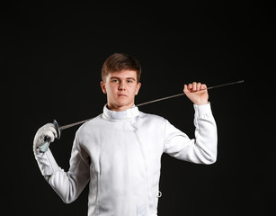 Young male fencer on dark background