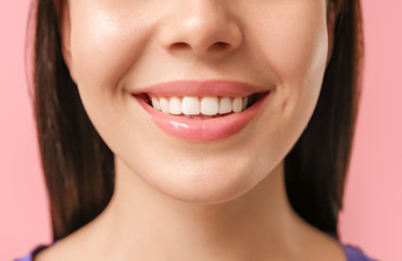 Young woman with healthy teeth on color background, closeup