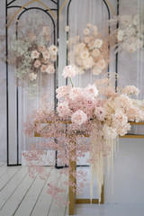 Decor for a luxury holiday wedding. Floral decoration with blooming flowers of peonies, roses, gypsophila and calla lily in white and pink colors.