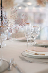 Decor for a luxury gala dinner. Table decorated with flowers of gypsophila in white and pink colors. Serving from plates, cutlery and glasses.